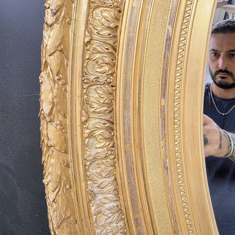 Large 19th oval mirror in gilded wood with gold leaf. Alternate view